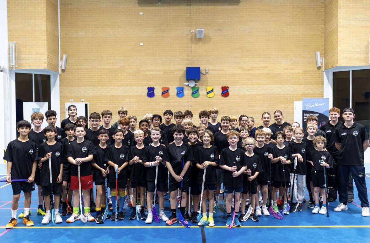 RISE Floorball Academy group photo of young players holding sticks in a gymnasium
